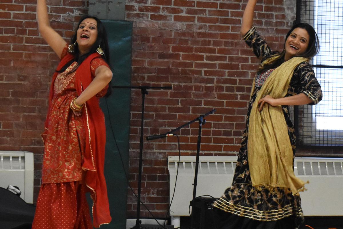 two bollywood dancers with arm raised in red and yellow