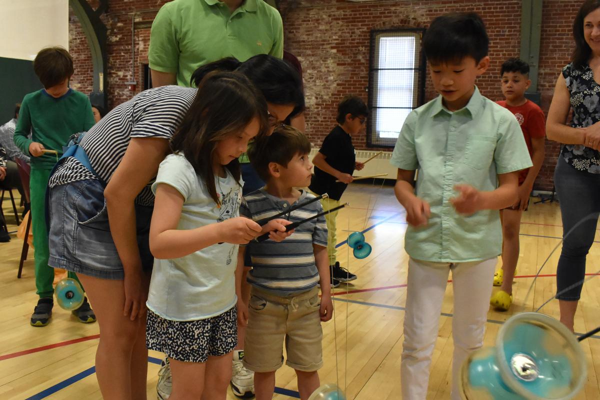adults watch three children test out chinese yoyo