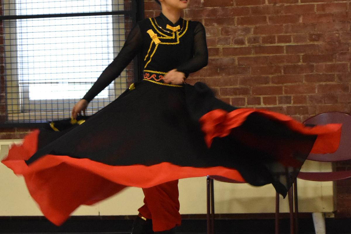 woman performs a dance in flowing red and black dress with bowls balanced on her head
